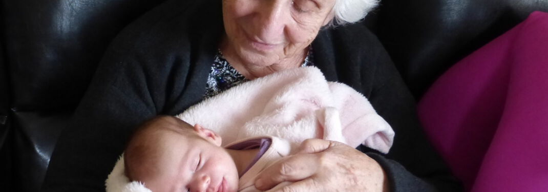 Eine alte Dame hält ein Baby in den Armen
